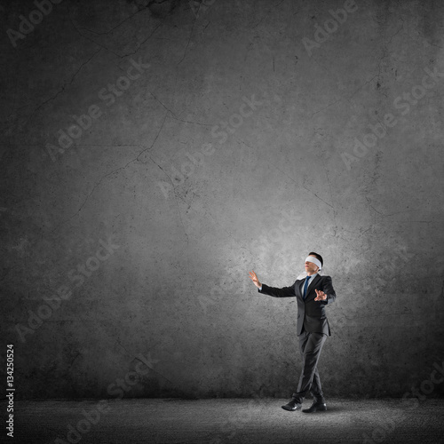 Business concept of risk with businessman wearing blindfold in empty concrete room