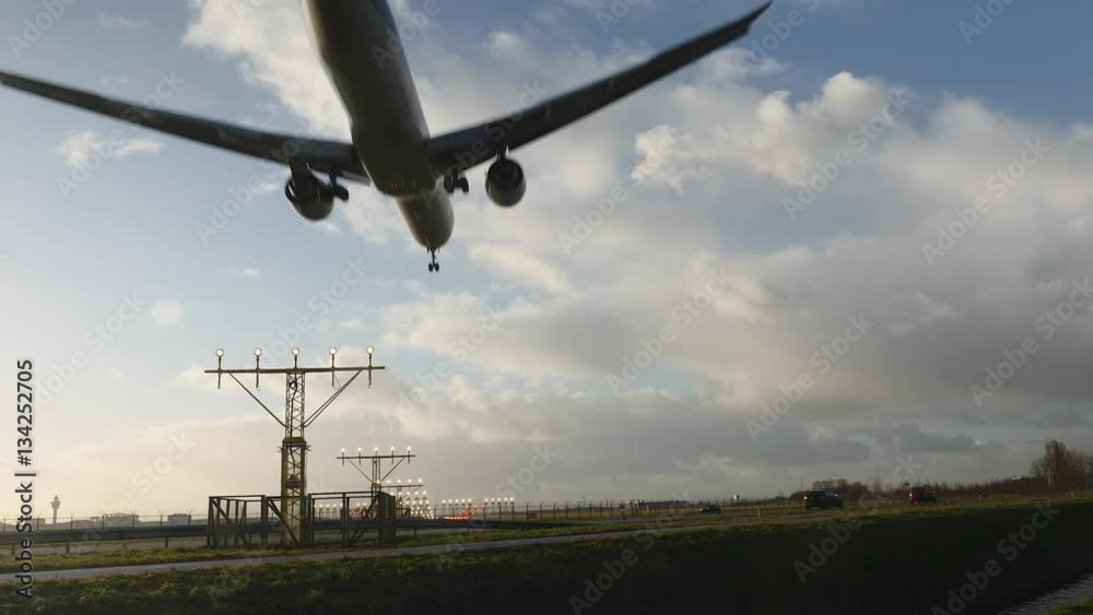 Plane flying into frame, landing on illuminated runway.