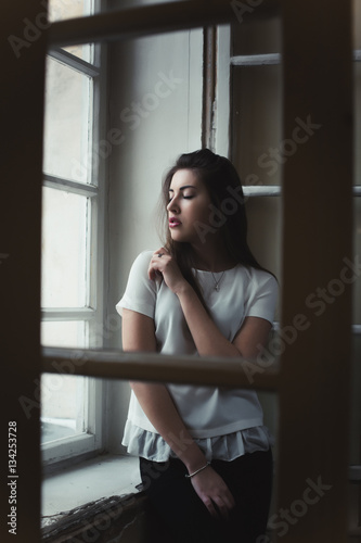 Attractive young brunette woman standing behind the window © vpavlyuk