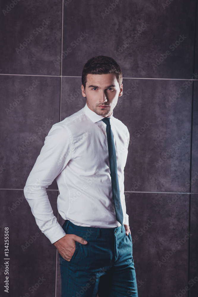 Handsome young businessman holding hands in pockets Handsome young businessman holding hands in pockets
