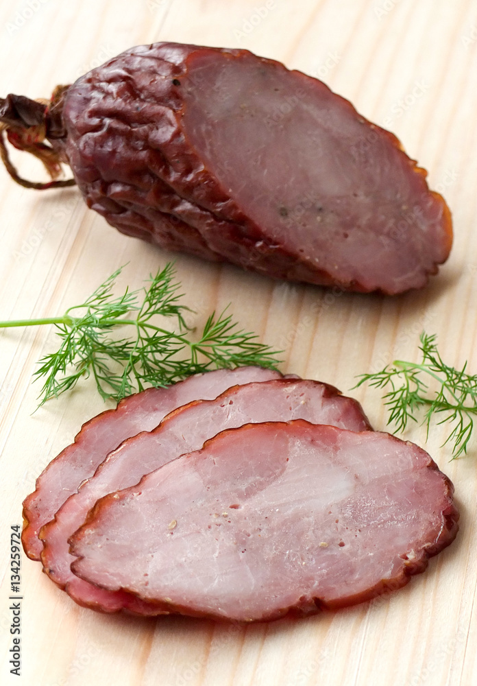 Smoked sausage with herbs on a wooden board Smoked sausage with herbs on a wooden board