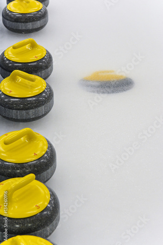 Yellow Curling Stones on ice sheet