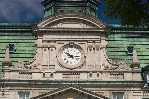 Clock of City Hall in Old Montreal, Quebec, Canada.  Mansard roof, fleur de lis, and rounded pediment architectural details of New French Imperialism architecture. photo