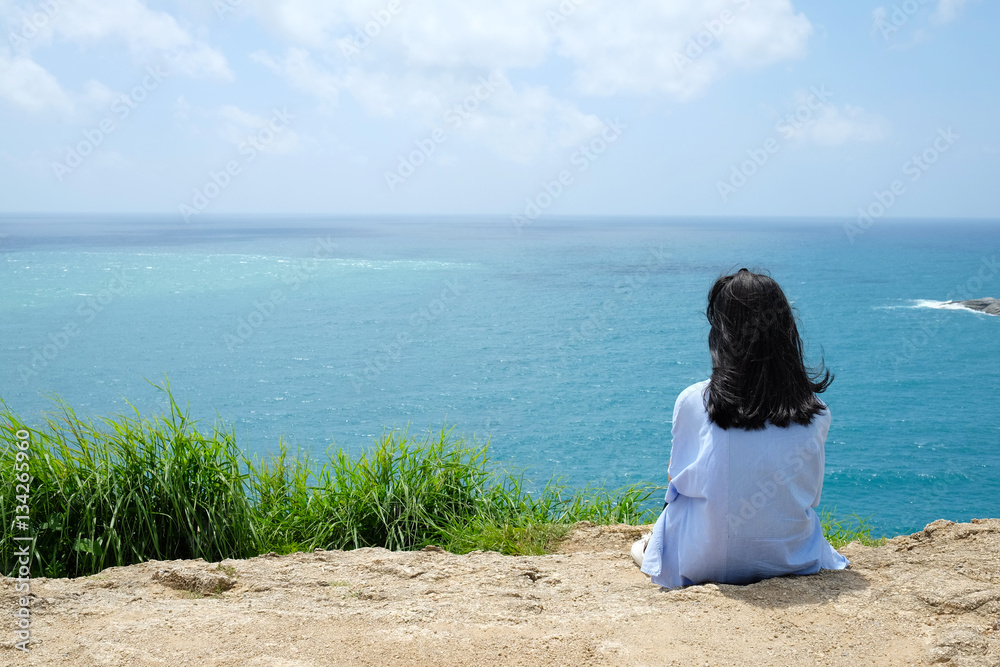 Back side of young girl sitting by the sea background