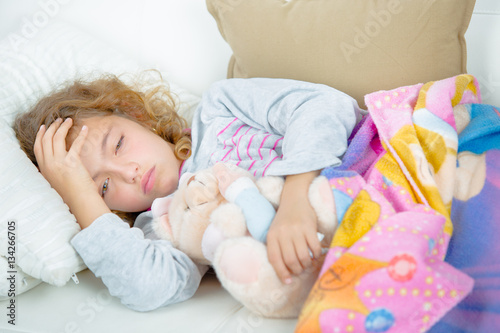 Young girl lying down holding head