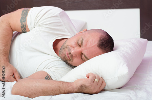 Muscular handsome young man with arm tattoos sleeping peacefully