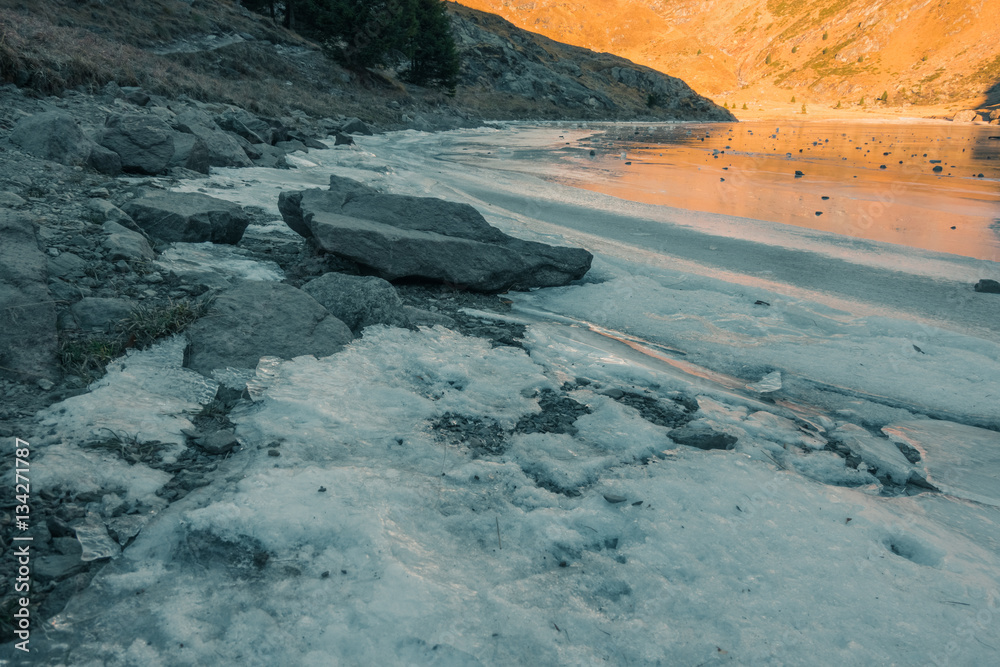 Fototapeta premium Iced lake between the mountains at sunset