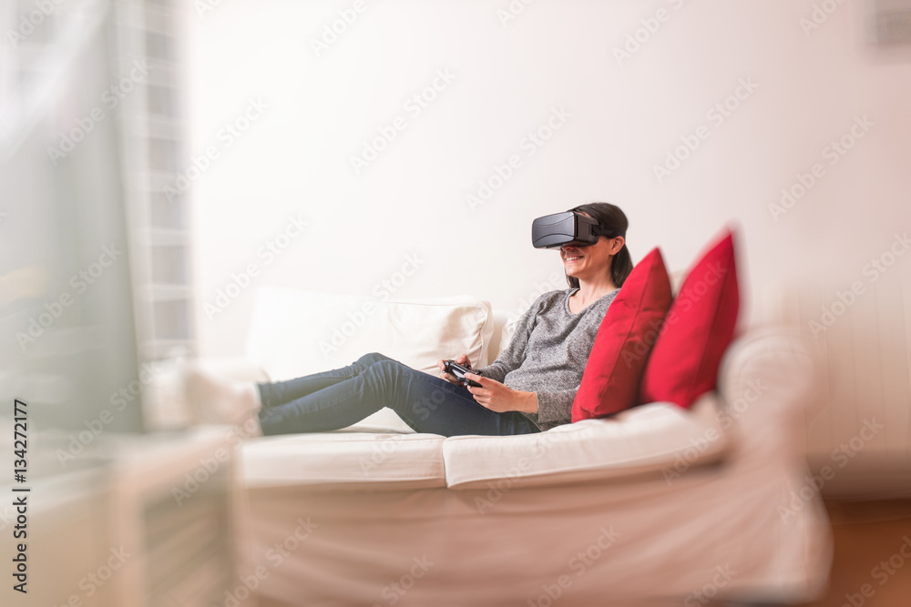 Young woman sitting on the sofa at home having fun playing a vir Young woman sitting on the sofa at home having fun playing a vir
