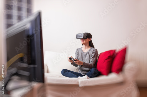Young woman sitting on the sofa at home having fun playing a vir