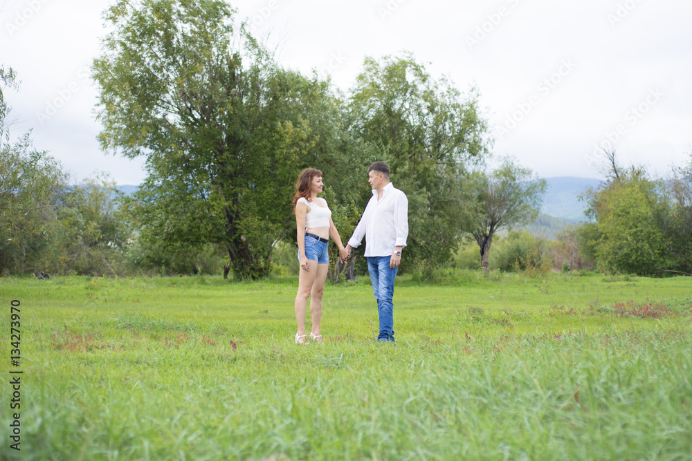 Lovers man and woman walking on green field. Lovers man and woman walking on green field.