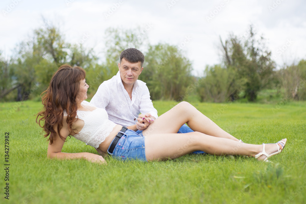 Lovers man and woman sitting on the green grass.