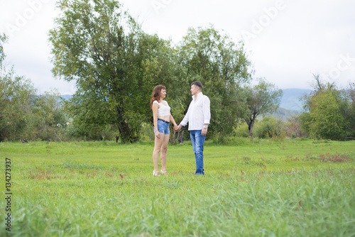 Lovers man and woman walking on green field.