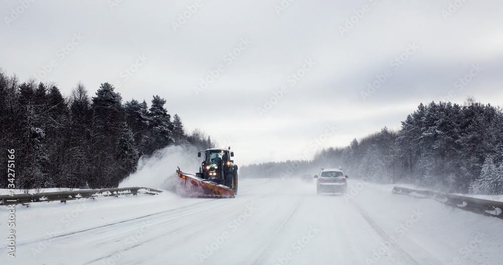 Bulldozer cleaning a asphalt road in winter forest highway Bulldozer cleaning a asphalt road in winter forest highway