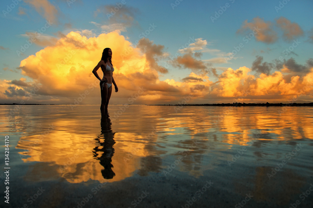 Silhouetted woman standing in a water at sunset on Taveuni Islan