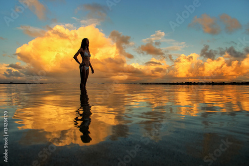 Silhouetted woman standing in a water at sunset on Taveuni Islan