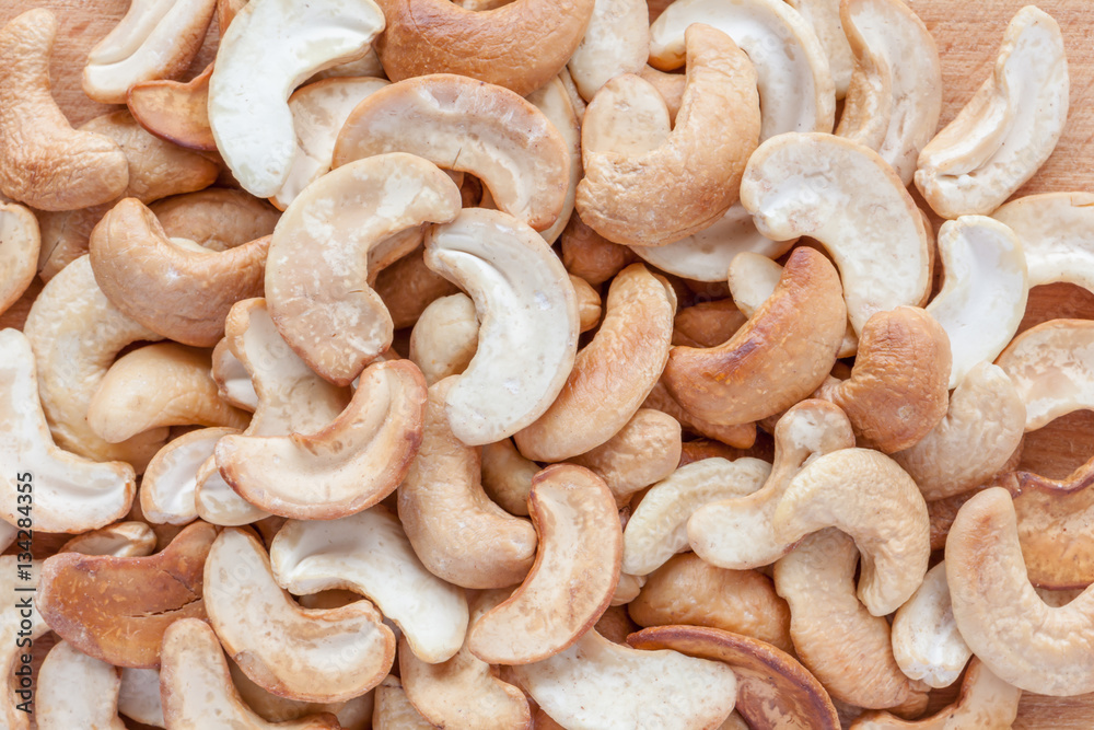 Close up pile of cashew nuts on wooden board background. Close up pile of cashew nuts on wooden board background.