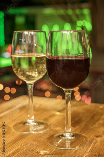 Red and white wine glasses on blurred lights background
