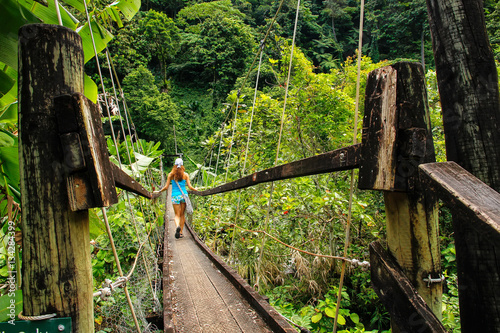 Young woman walking on suspension bridge over Wainibau stream, L photo