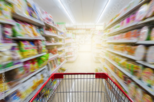 Supermarket aisle with empty red shopping cart