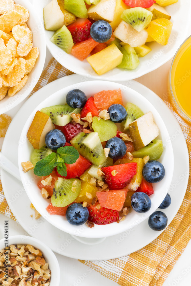 breakfast with fruit salad and corn flakes on table, vertical