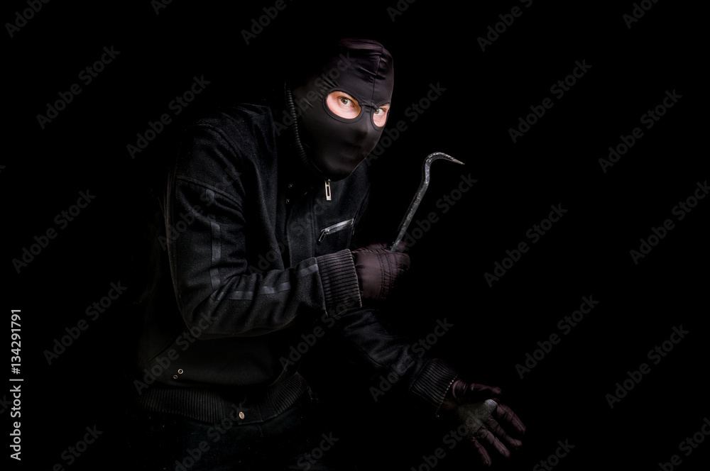 Masked thief in balaclava with crowbar isolated on black Masked thief in balaclava with crowbar isolated on black