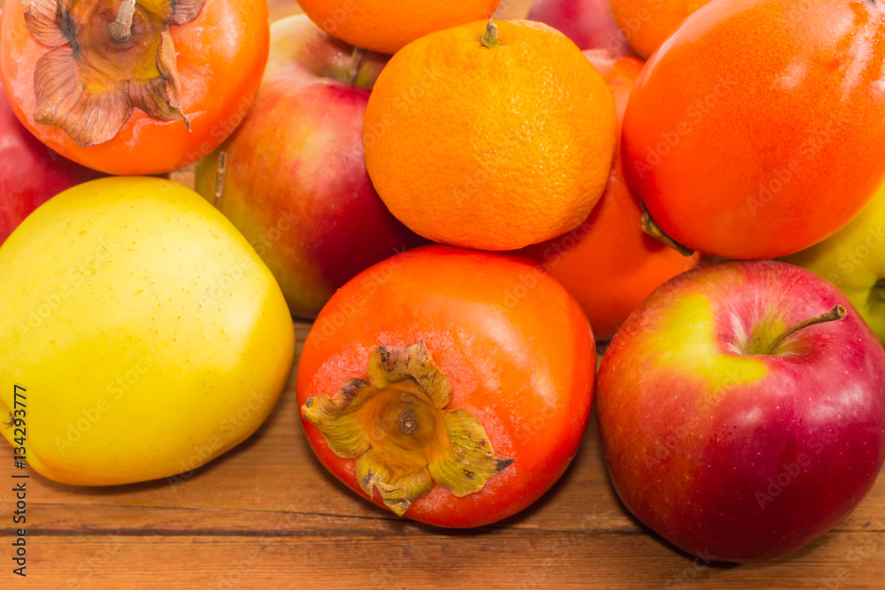 Pile of different fruits on wooden surface closeup