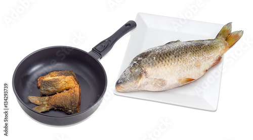 Fried slices of carp on pan and whole frozen carp