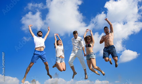 Image of five energetic people jumping at the beach