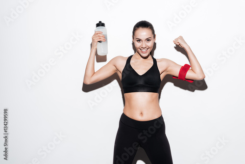 Happy young woman athlete with bottle of water showing biceps © Drobot Dean