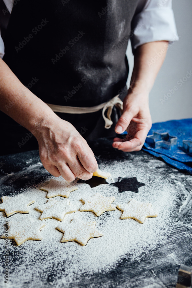 Hands of cook putting cookies to the flour. Vertical studio shot. Hands of cook putting cookies to the flour. Vertical studio shot.