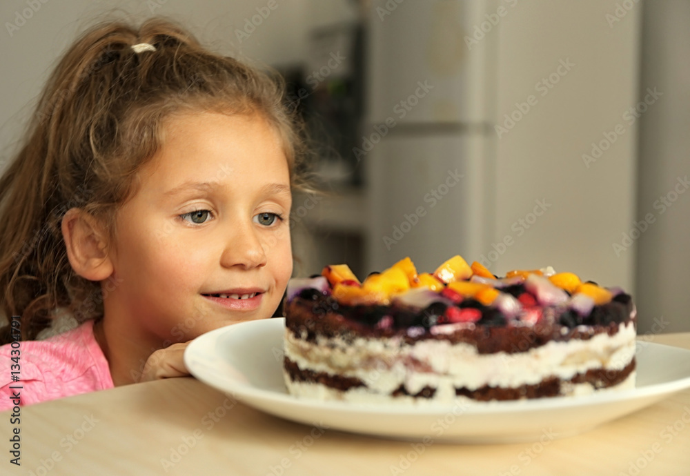 Cute little girl going to taste sweet cake left on kitchen table Cute little girl going to taste sweet cake left on kitchen table