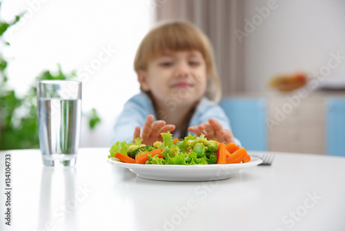 Small girl refusing to eat vegetable salad