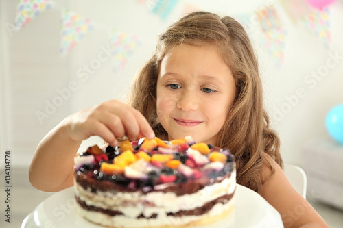 Pretty little girl with birthday cake at home, close up