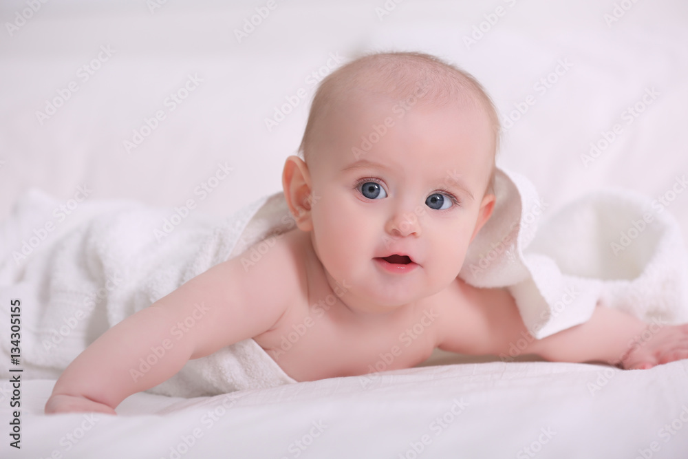 Cute funny baby with towel lying on bed at home Cute funny baby with towel lying on bed at home