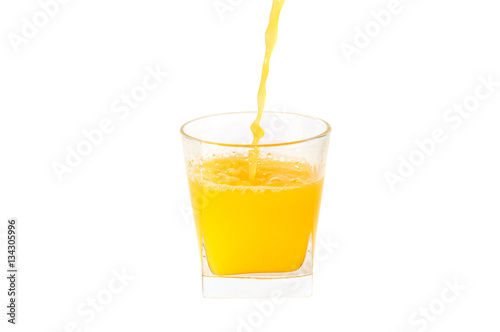 The juice is pouring into a glass. Isolated on white.