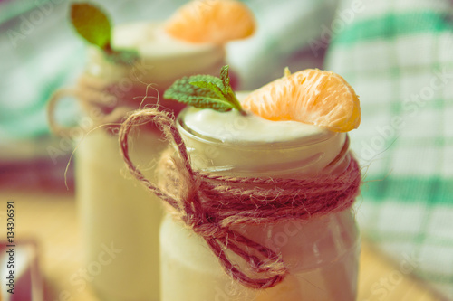 Fresh organig natural white yogurt in glass jars with tangerine photo