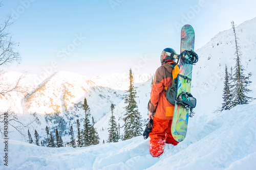 Freerider man is standing on the mountainside in a helmet and wi