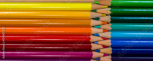 Row of colorful pencils rainbow order on wooden table