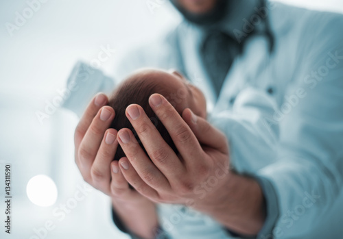 Pediatrician holding a newborn baby boy in hospital