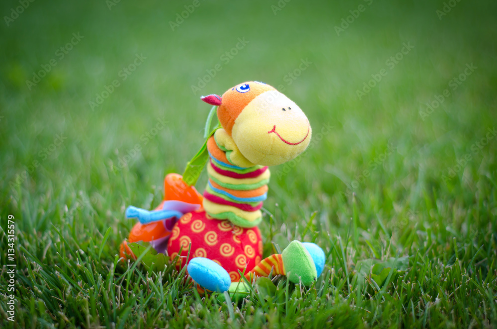A toy giraffe in the grass