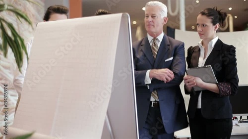 youngbusinessman making presentation of project to senior investior group of business people taking notes and make plans on white  flip board and tablet computer at startup office photo