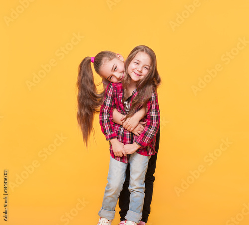 Happy funny girl sisters hugging and laughing