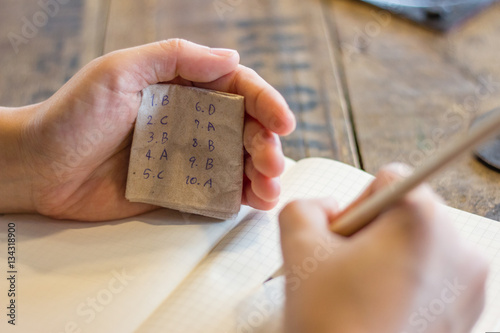 People cheating in test with answer piece of paper