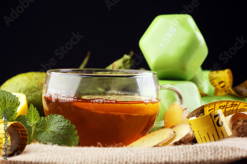 ginger tea - fitness liefestyle concept with tea, dumbells and measure tape - Healthy tea detox photo