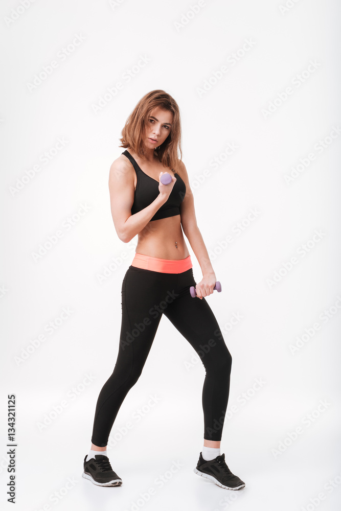 Fototapeta premium Concentrated young fitness lady make exercises with dumbbells