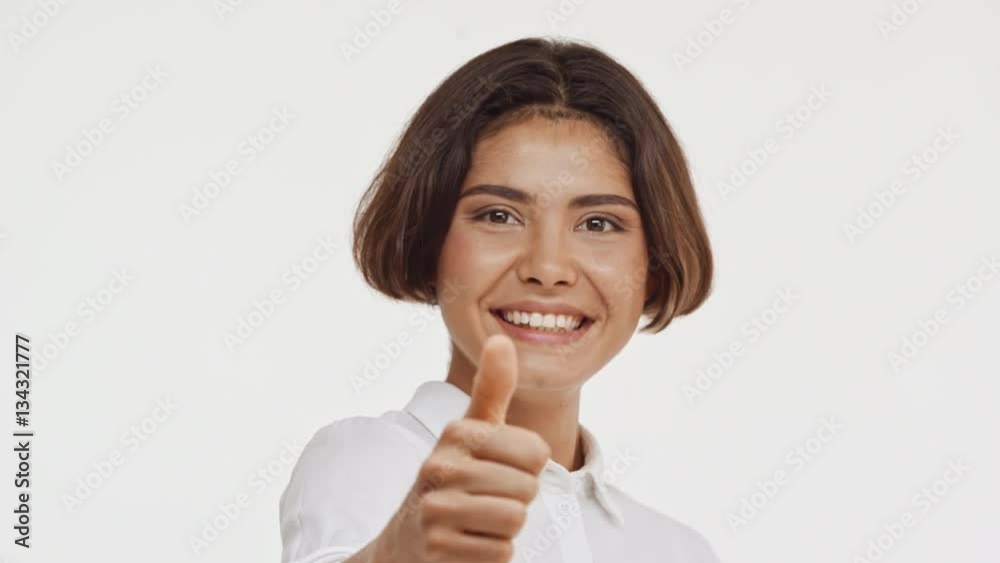 Young beautiful brunette east asian female in shirt actively smiling showing ok with thumb on white background Young beautiful brunette east asian female in shirt actively smiling showing ok with thumb on white background