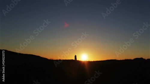 Man and woman stand embracing at sunset sky silhouetted. Couple in love hold kissing on hill outdoors. Love unity togetherness relationship concept