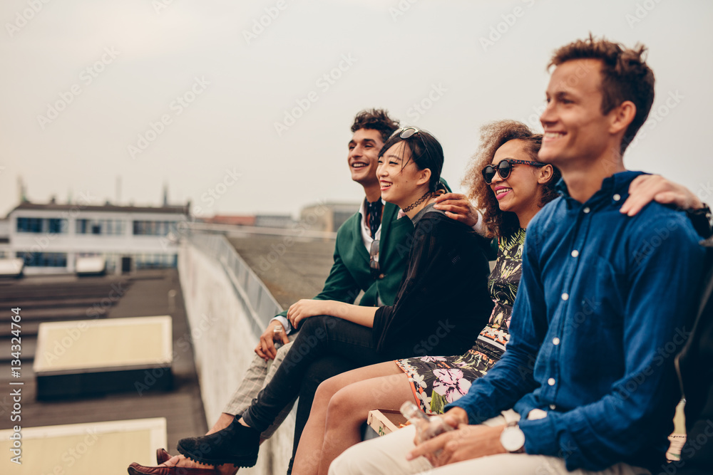 Friends sitting together on rooftop - obrazy, fototapety, plakaty 