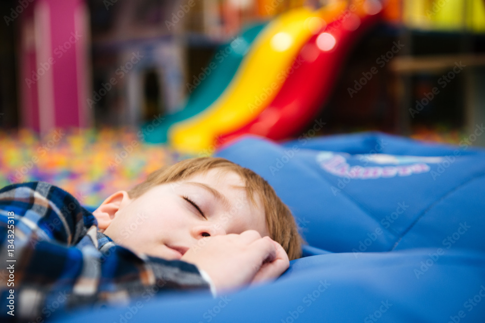 Tired exhausted little boy sleeping at indoor amusement park Tired exhausted little boy sleeping at indoor amusement park