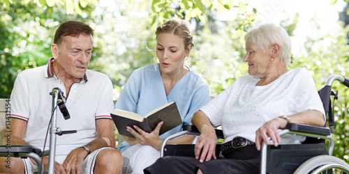 Carer reads a book to the elderly persons photo
